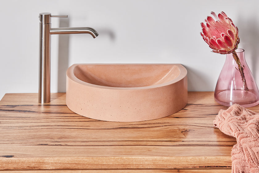 Close up of timber vanity top with black sap line features and peach concrete basin