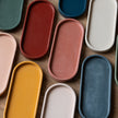 Assorted colorful concrete oval trays on a wooden surface
