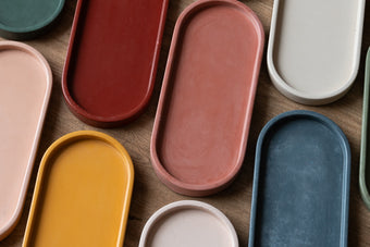 Assorted colorful concrete oval trays on a wooden surface