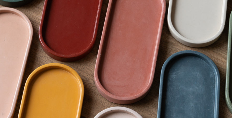 Assorted colorful concrete oval trays on a wooden surface