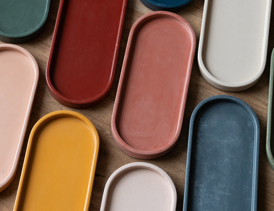 Assorted colorful concrete oval trays on a wooden surface